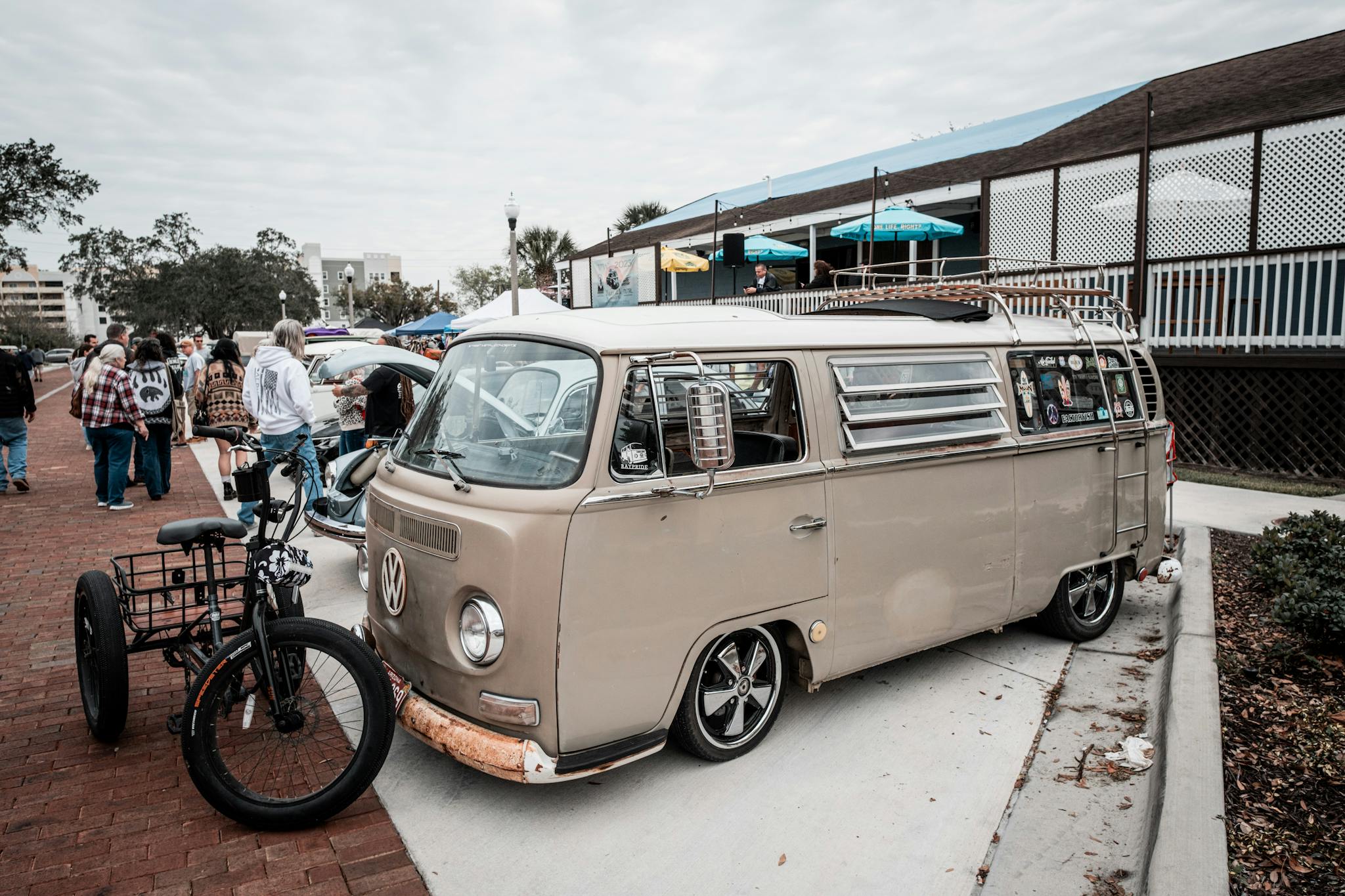Classic VW van displayed at an outdoor vintage car show with crowd.
